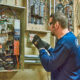 The electrician intensely examines a circuit breaker panel, wearing protective gloves and glasses in the utility room. With expertise in smart homes, the electrician optimizes surge protection to meet modern safety standards.